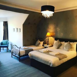 Un dormitorio con dos camas y una lámpara de araña. en Ardenlee Guest House, en Edimburgo
