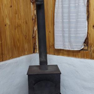 Una estufa negra en una habitación con ventana. en El Cipresal- Pichi Ruka, en San Martín de los Andes