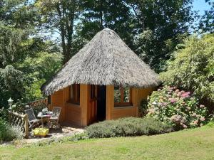 une petite cabane avec un toit de paille dans un jardin dans l'établissement La Cabane de Cécile-la Hutte, à Étretat