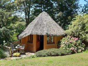 a small hut with a straw roof in a garden at La Cabane de Cécile-la Hutte in Étretat
