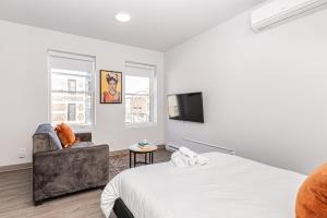 a bedroom with a bed and a chair and a television at Wonderful New Studio close to Mount Royal By Den Stays in Montréal