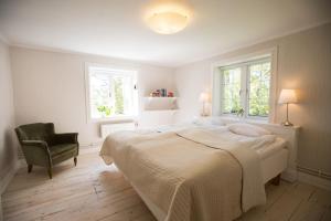 a bedroom with a bed and a chair and two windows at Lilla Sörgården in Kungsberga