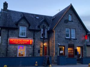 a building with a red sign in front of it at Richmond House Hotel in Fort Augustus