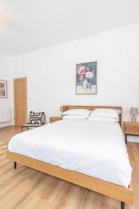 - une chambre avec un grand lit et des draps blancs dans l'établissement Banc Apartment 1, à Porthmadog