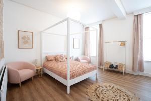 a white bedroom with a canopy bed and a chair at Banc Apartment 1 in Porthmadog