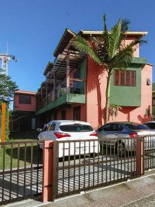 two cars parked in front of a house with a fence at Morada Canto Norte - Apartamentos Beira Mar in Garopaba