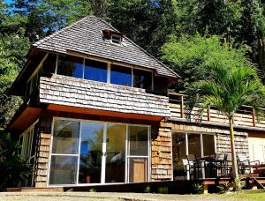 una casa con ampie finestre e una palma di Manta Lodge avec 4x4 Pleine nature a Haapu