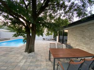 patio z drewnianym stołem i krzesłami obok drzewa w obiekcie Villa ELENA w Medziugorie