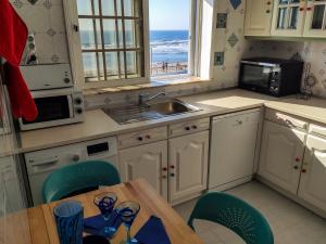 uma cozinha com uma mesa e cadeiras e um lavatório em Brisa do Mar da Vagueira em Praia da Vagueira