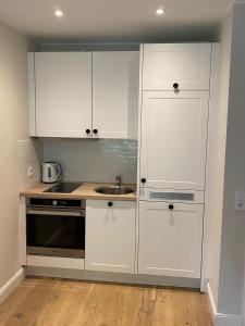 a kitchen with white cabinets and a sink at Ferienwohnung Pelzerhaken in Pelzerhaken