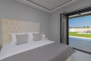 a bedroom with a white bed and a large window at Nimar Villas in Gaïtánion +99 photos
