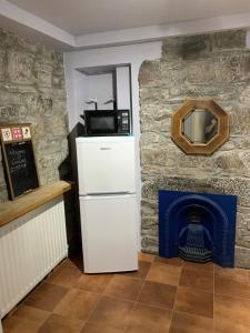 a refrigerator in a room with a stone fireplace at The Old Chemist in Cullen