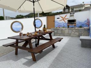 einem Picknicktisch mit einer Bank und einem Regenschirm in der Unterkunft Casa Da Villa in Vila Praia de Âncora
