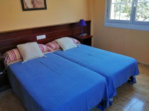 1 dormitorio con 2 camas con sábanas azules y ventana en Apartamentos Turísticos San Breixo, en Carballo