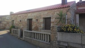 ein Steingebäude mit einem Zaun und Blumen darauf in der Unterkunft O Iniño casita rural costera in O Grove