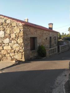 a stone building with a window on a street at O Iniño casita rural costera in O Grove