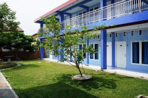 un árbol frente a un edificio azul en Kenari Residence en Pekanbaru