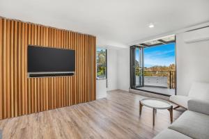 a living room with a flat screen tv on a wooden wall at TARA5- UNWIND IN LUXURY in Mooloolaba