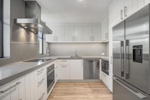 a kitchen with white cabinets and stainless steel appliances at TARA5- UNWIND IN LUXURY in Mooloolaba