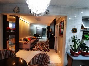 uma sala de estar com um sofá e um lustre em Apartamento FRENTE PARA 0 MAR - PÉ NA AREIA - 3 SUITES COM AR CONDICIONADO, 2- VAGAS DE GARAGEM - FINAMENTE DECORADO - PRAIA DO MORRO-INTERNET -WI-FI -TV COM SERVIÇOS DE DISNEY PLUS - NETFLIX -HBO MAX -STAR MAX - JOGOS AMAZON FIRE STICK - ALEXIA em Guarapari