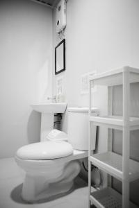 a white bathroom with a toilet and a shelf at Suyog Life Siargao in General Luna