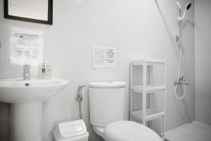 a white bathroom with a toilet and a sink at Suyog Life Siargao in General Luna