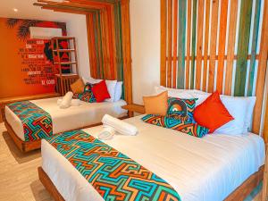 two beds with colorful pillows in a room at In Di House of Reggae Boutique in San Andrés