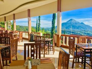 un restaurante con mesas y sillas y una montaña de fondo en Inna Tretes Hotel & Resort, en Prigen