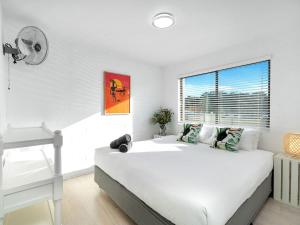 a white bedroom with a bed and a window at Bayswell by Experience Jervis Bay in Huskisson