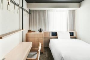 1 dormitorio con 2 camas, escritorio y ventana en REF Matsuyama City Station by VESSEL HOTELS, en Matsuyama