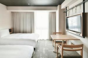 松山市にあるREF Matsuyama City Station by VESSEL HOTELSのベッド2台とテーブルが備わるホテルルームです。