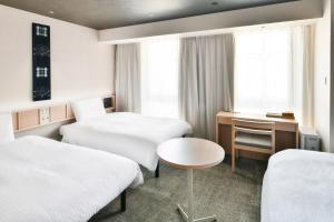 松山市にあるREF Matsuyama City Station by VESSEL HOTELSのベッド2台とデスクが備わるホテルルームです。