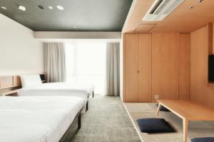 ein Hotelzimmer mit zwei Betten und einem Tisch in der Unterkunft REF Matsuyama City Station by VESSEL HOTELS in Matsuyama