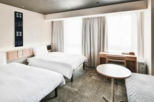 a hotel room with two beds and a desk at REF Matsuyama City Station by VESSEL HOTELS in Matsuyama
