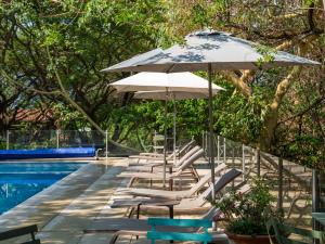 a row of chairs and umbrellas next to a swimming pool at Hotel Amate del Rio in Malinalco