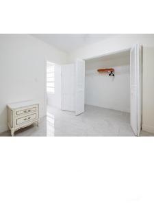 a white room with a cabinet and a table at Spacious 4 bdr 2 bath home 10min to the beach Aventura mall in Hallandale Beach