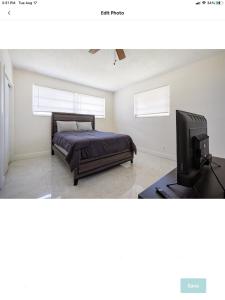 a bedroom with a bed and a flat screen tv at Spacious 4 bdr 2 bath home 10min to the beach Aventura mall in Hallandale Beach