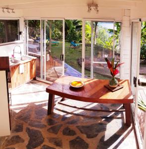 uma cozinha e sala de estar com uma mesa de madeira em Manta Lodge avec 4x4 Pleine nature em Haapu