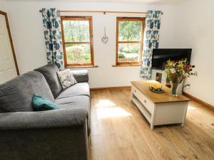 a living room with a couch and a tv at Groom's Cottage in Allanton