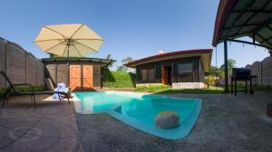 a swimming pool with an umbrella and a house at Cabaña El Monasterio in Fortuna