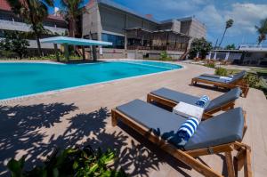 a pool with two lounge chairs next to a building at Kristal Hotel Kupang in Kupang