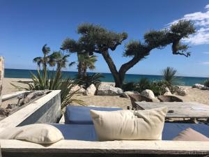 a bench on the beach with a table and the ocean at La maison de Virginie 6 a 12 personnes -300 m de la plage- vélos a disposition in Saint Cyprien Plage