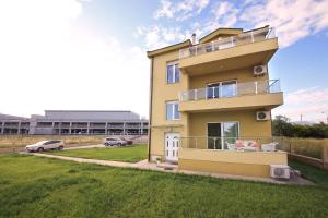 a yellow house with a lawn in front of it at Apartments Aleksandra in Podgorica