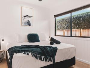 a white bedroom with a bed with a window at Poplar Villa - 1 Poplar Lane in Evans Head