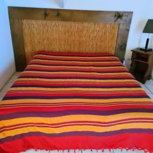 Una cama con una manta de rayas de colores. en Appartement de 2 chambres avec vue sur la mer piscine partagee et jardin clos a Bois des Nefles Saint Paul, en Le Bois de Nèfles