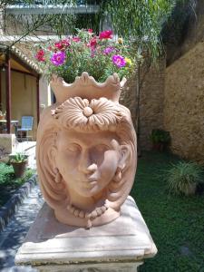 Eine Vase mit einem Gesicht drauf mit Blumen drin in der Unterkunft Giardinetto Papale, centralissimo in Caltagirone