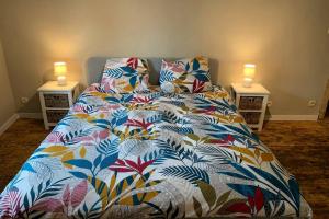 a bed with a colorful comforter and two night stands at Au bord du Ny in Hotton