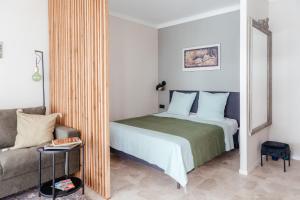 een slaapkamer met een bed, een bank en een spiegel bij ´La Primavera ´ in Roquebrune-Cap-Martin