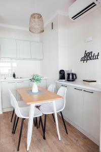 a white kitchen with a wooden table and white chairs at ´La Primavera ´ in Roquebrune-Cap-Martin