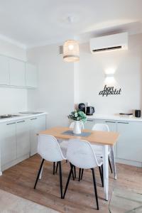 a white kitchen with a wooden table and chairs at ´La Primavera ´ in Roquebrune-Cap-Martin